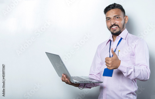 Man with laptop in hand showing thumbs up towards the camera