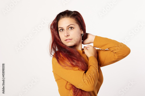 portrait of a Hispanic woman in an orange sweater and a beautiful expression with her arms.