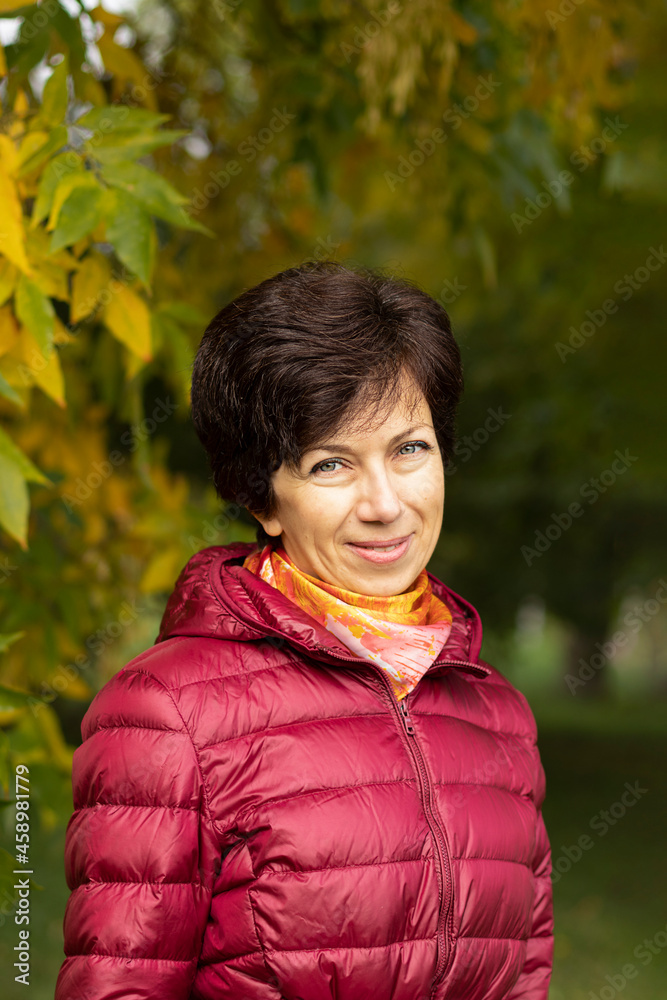 Vertical portrait of an adult cute woman in a bright burgundy jacket in autumn park, a Jewish woman, golden autumn. Vertical portrait of an adult cute woman in a bright burgundy jacket in autumn park, a Jewish woman, golden autumn.