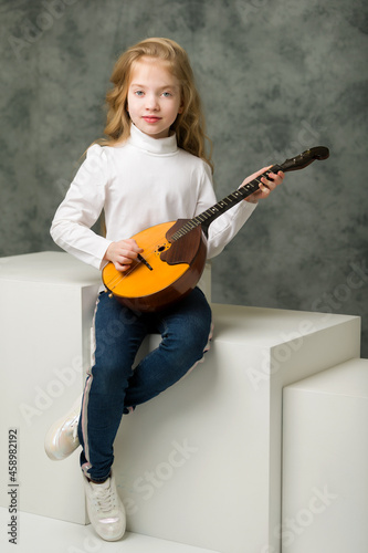 Cute little girl is playing dombra. photo