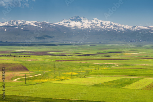 View of the ancient extinct Aragats volcano and the fertile valley at its foot with agricultural lands sown in early spring in Armenia. © EdNurg