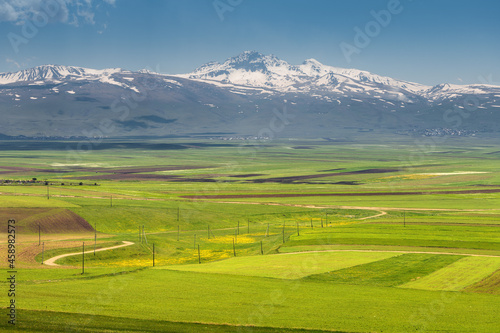 View of the ancient extinct Aragats volcano and the fertile valley at its foot with agricultural lands sown in early spring in Armenia.