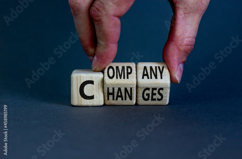 Company changes symbol. Businessman turns wooden cubes and changes the word 'company' to 'changes'. Beautiful grey background. Company changes and business concept. Copy space.