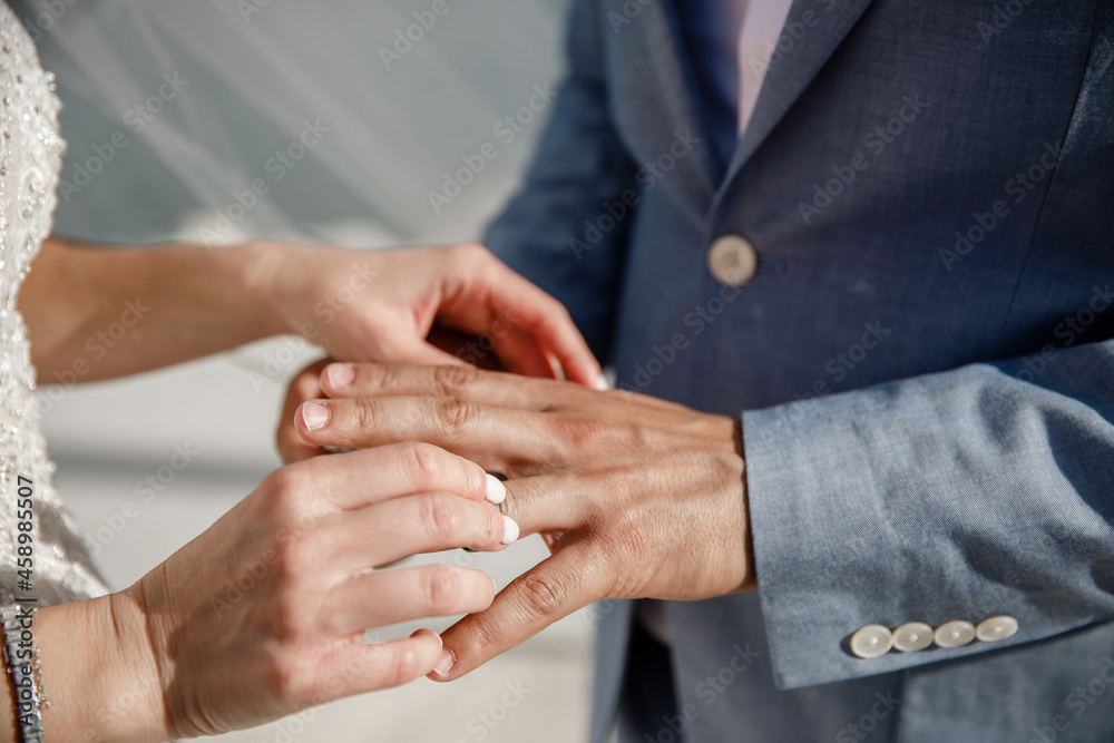 Obraz premium The bride puts a ring on the grooms finger The moment of exchanging of the rings of newlyweds Horizontal frame Wedding day Ceremony Wedding hands with rings Close up
