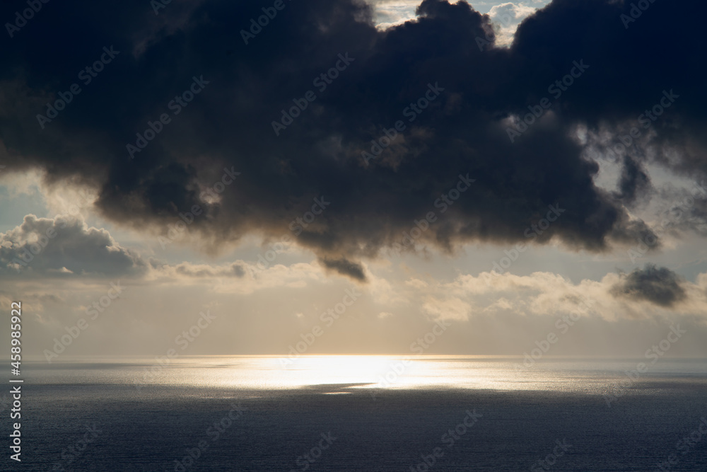 Fototapeta premium The sun breaks through heavy clouds over the sea during a storm