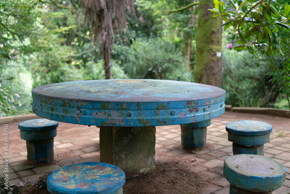 Old table and benches in the shade of trees in a park on a summer cloudy day Old table and benches in the shade of trees in a park on a summer cloudy day