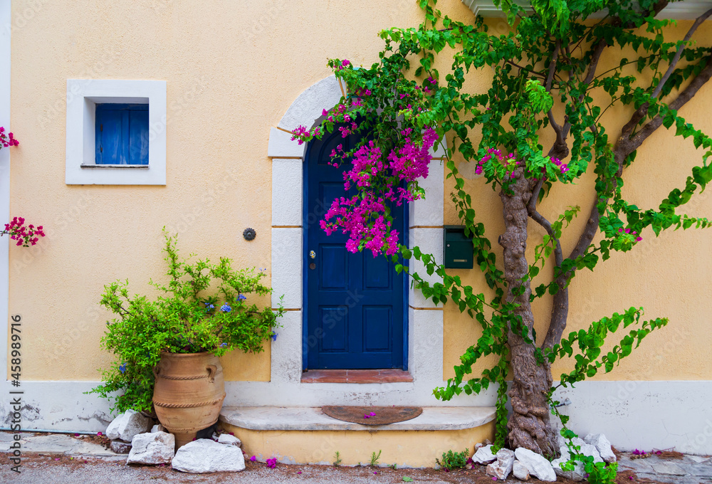 Colorful blue door of traditional greek house with yellow walls at Asos village. Assos peninsula famous and extremely popular travel destination in Cephalonia, Greece, Europe.