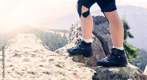 Tourist legs in hiking boots. Trekking shoes. Against the background of mountains and rocks. © amdre100