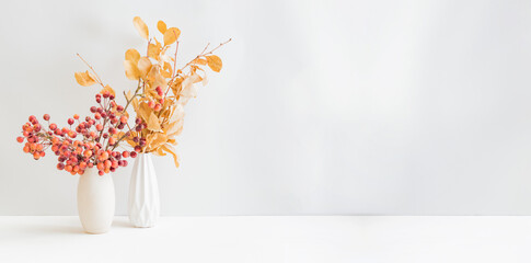 Home interior with decor elements. Dry autumn leaves in a vase on a light background