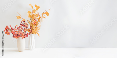 Home interior with decor elements. Dry autumn leaves in a vase on a light background