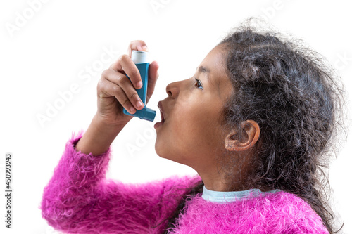 Close-up portrait of cute 5 year old girl using his asthma inhaler, profile view white background. photo