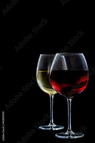 Two glasses of red an white wine on black background.