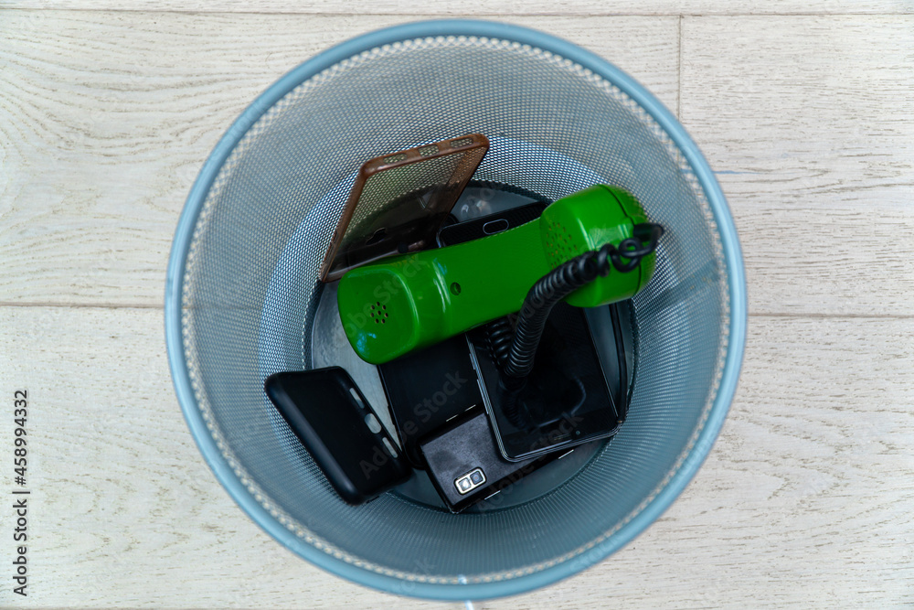 The evolution of telephones and accessories for them. Old phones and cases in the trash