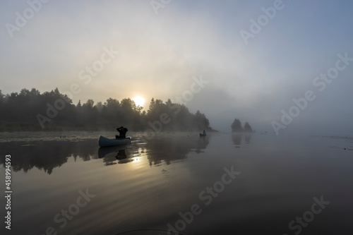 Early morning. Fog on the river. Beautiful sunrise in the summer by the river. Mystical morning on the river. A man floats in a boat against the background of dawn.
