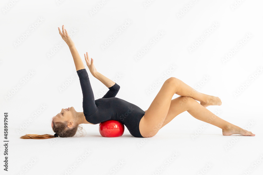 slim artistic teenager girl in black leotard trains on white background with red ball in her hands in rhythmic gymnastic exercise, children's professional sports slim artistic teenager girl in black leotard trains on white background with red ball in her hands in rhythmic gymnastic exercise, children's professional sports