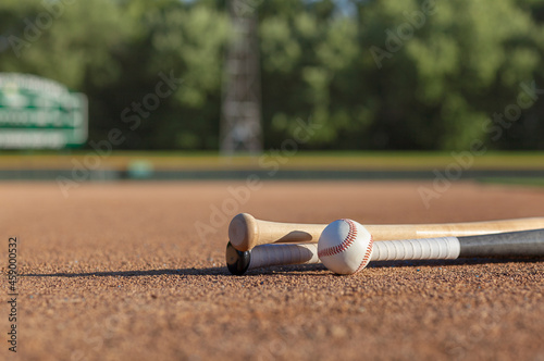 Wall Mural Low angle view of a baseball and bats on dirt infield of baseball park in aftern