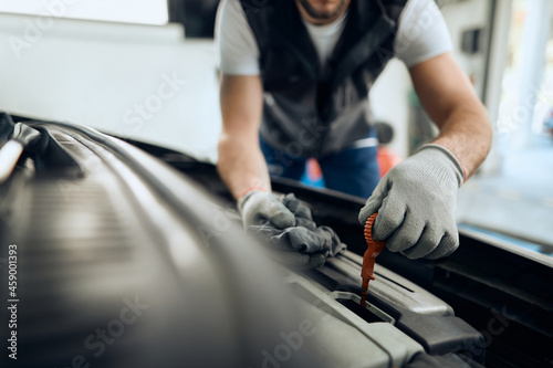 Close-up of car mechanic checks motor oil at repair shop. © Drazen