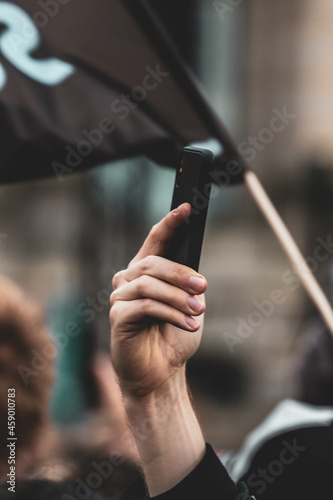 Mann filmt mit Handy auf einer Demo