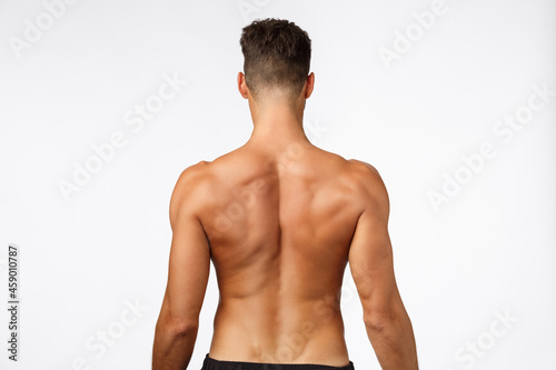 Attractive sportsman rear view, masculine strong back, athlete posing from behind, showing perfect body, muscles and abs, standing white background, promote workout, gym membership and fitness