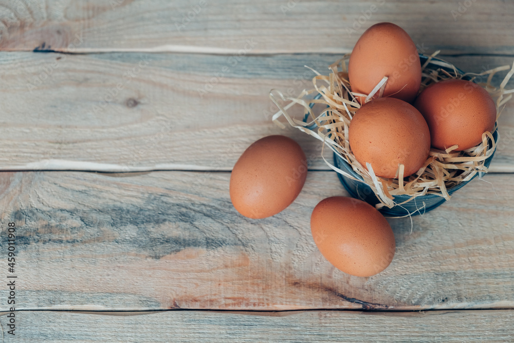 Chicken eggs on decorative straw in a basin on a wooden table. Chicken eggs on decorative straw in a basin on a wooden table.