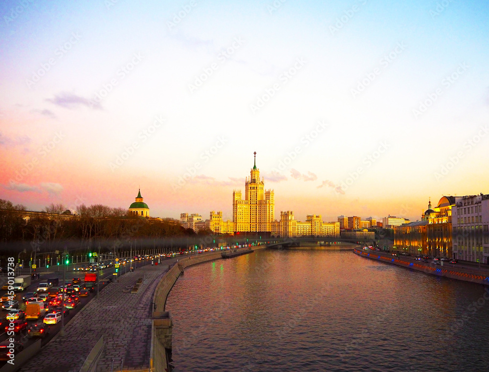 Fototapeta premium view of the sunset on the river, a residential skyscraper on Kotelnicheskaya Embankment, Moscow River, Bolshoy Ustinsky bridge. Moscow, Russia