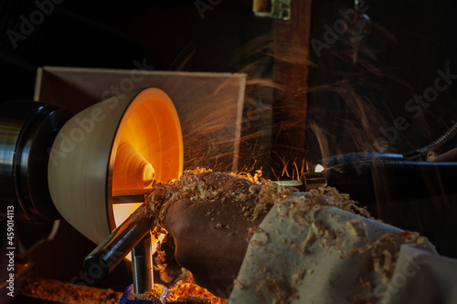 A wooden bowl being turned by a man on a woodturning lathe.A craftsman at work.Sawdust is flying. photo