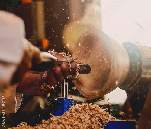 A wooden bowl being turned by a man on a woodturning lathe.A craftsman at work.Sawdust is flying.
