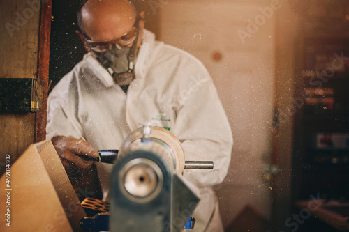 A wooden bowl being turned by a man on a woodturning lathe.A craftsman at work.Sawdust is flying. photo