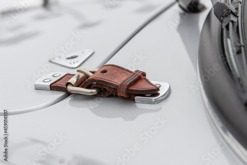 Vintage leather buckle on hood of sports car clasps the door down securly while driving photo