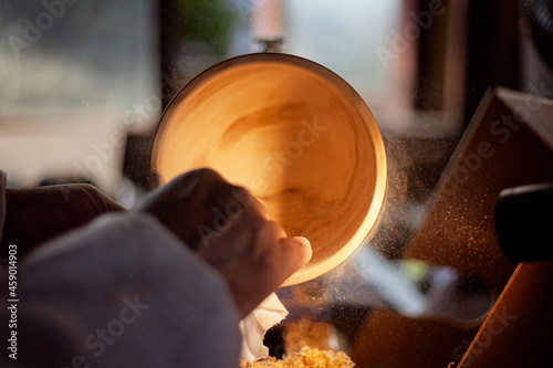 A wooden bowl being turned by a man on a woodturning lathe.A craftsman at work.Sawdust is flying. photo