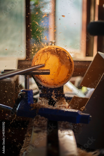 A wooden bowl being turned by a man on a woodturning lathe.A craftsman at work.Sawdust is flying. photo