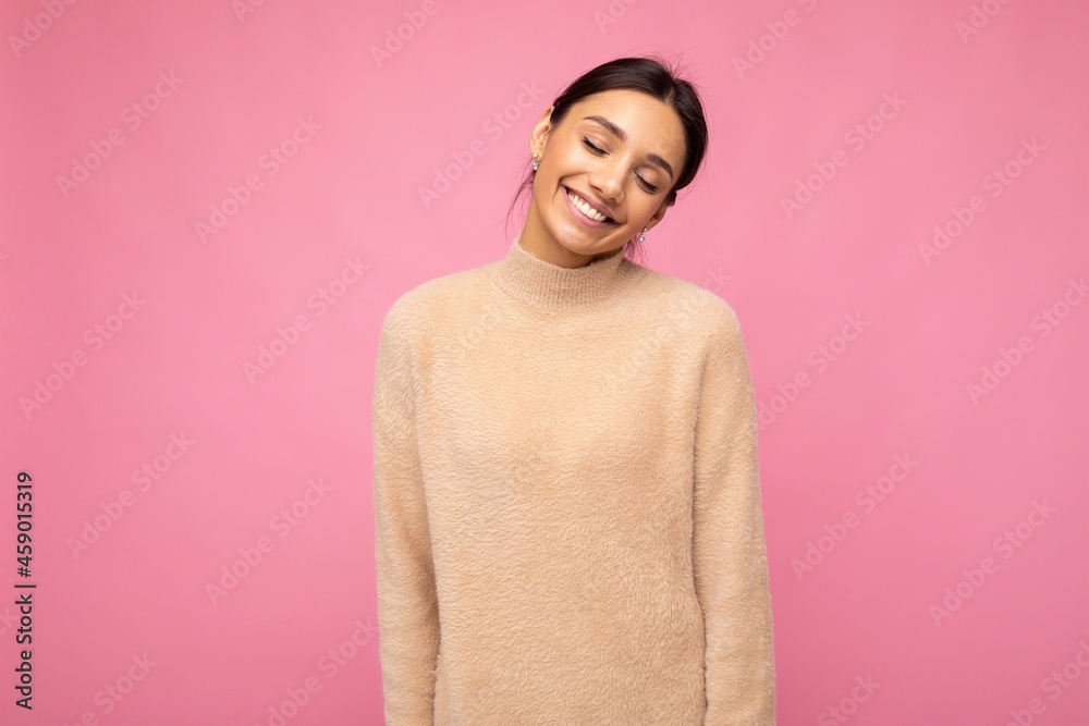 Portrait of beautiful positive cheerful cute smiling young brunette woman in casual sweater isolated on pink background with copy space
