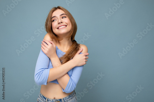 Photo of attractive cute happy emotional young woman poising isolated on background wall with free space wearing trendy casual clothes © Ivan Traimak