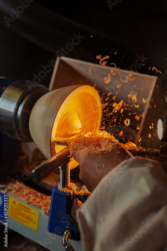A wooden bowl being turned by a man on a woodturning lathe.A craftsman at work.Sawdust is flying. photo