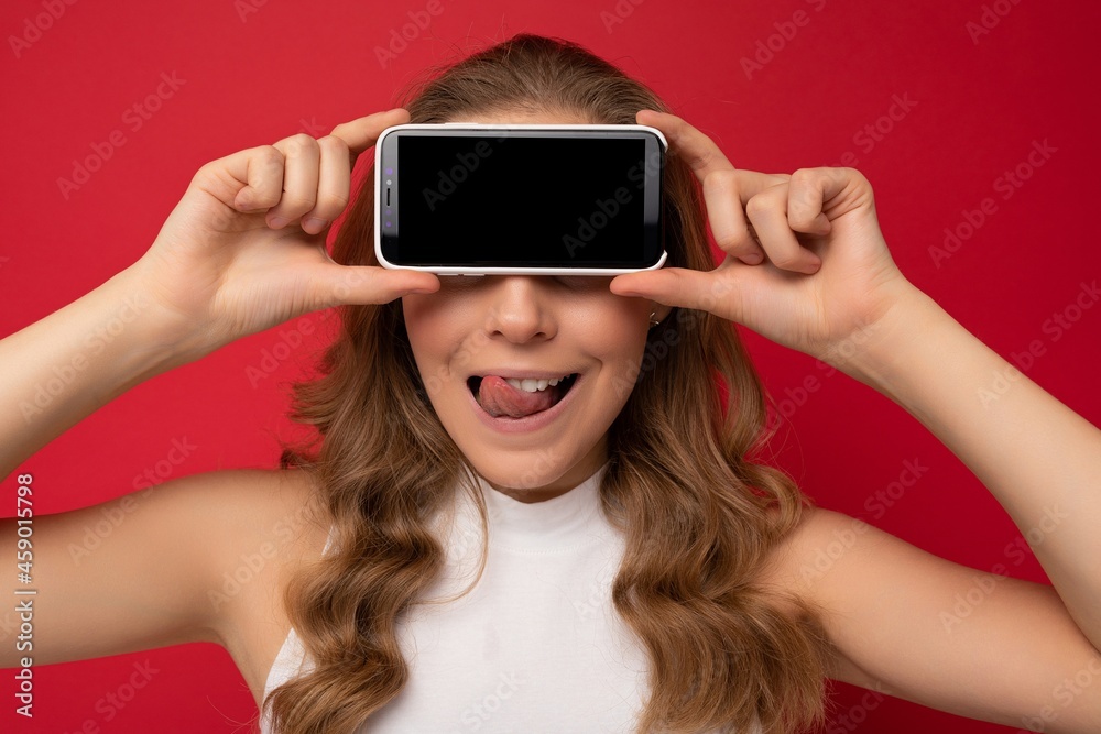 closeup Photo of beautiful smiling young woman good looking standing isolated on background with copy space holding smartphone showing phone in hand with empty screen display for mockup