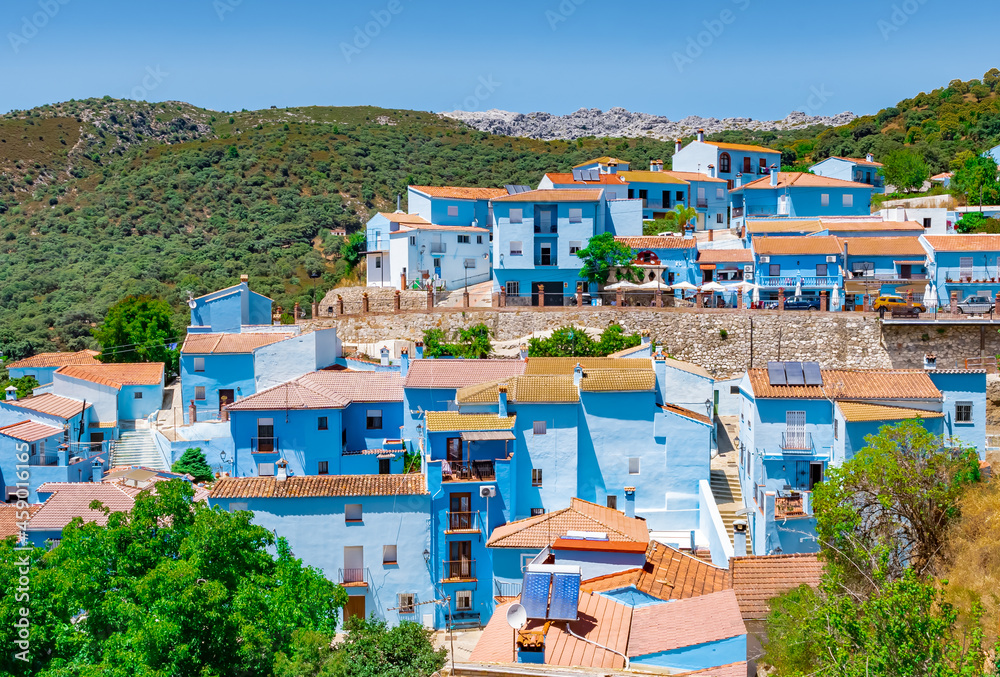 Pueblo con casa pintadas de azul en la sierra entre montañas desde Júzcar, en la provincia de Málaga, Andalucía, España.