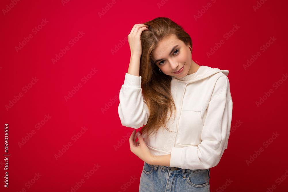 Young beautiful dark blonde woman with sincere emotions isolated on background wall with copy space wearing casual white hoodie. Positive concept