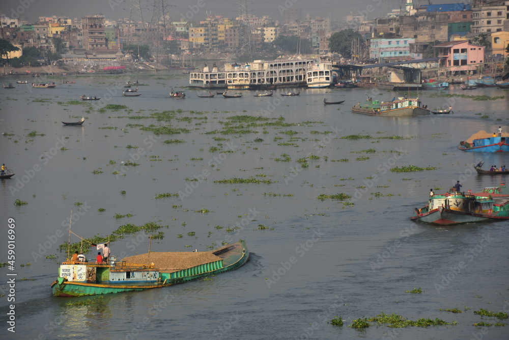 Obraz premium バングラデシュのダッカ。 川沿いの古い街並み。 川を進むタンカー。