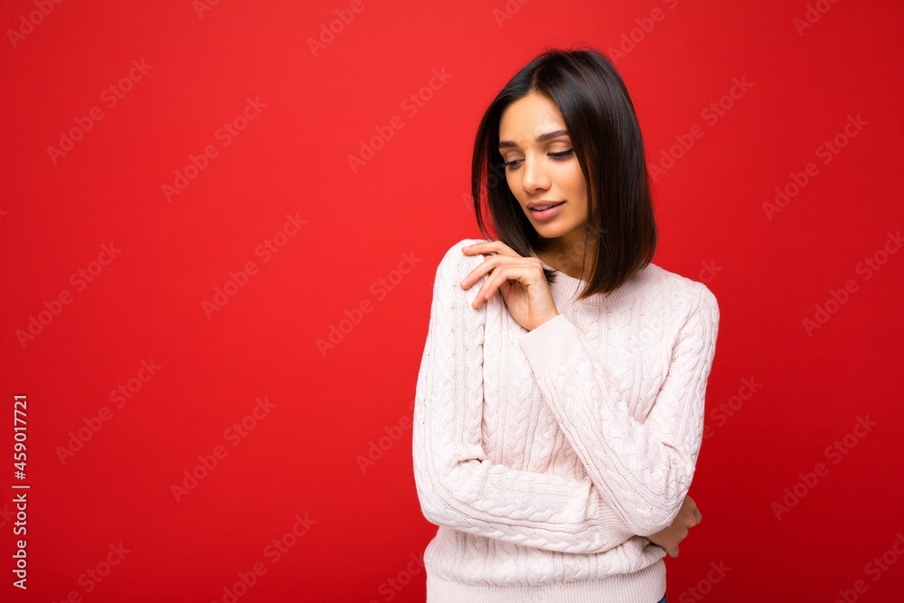 Attractive cute nice adorable tender young brunette woman in casual light knitted sweater isolated on red background with free space and enjoying Attractive cute nice adorable tender young brunette woman in casual light knitted sweater isolated on red background with free space and enjoying