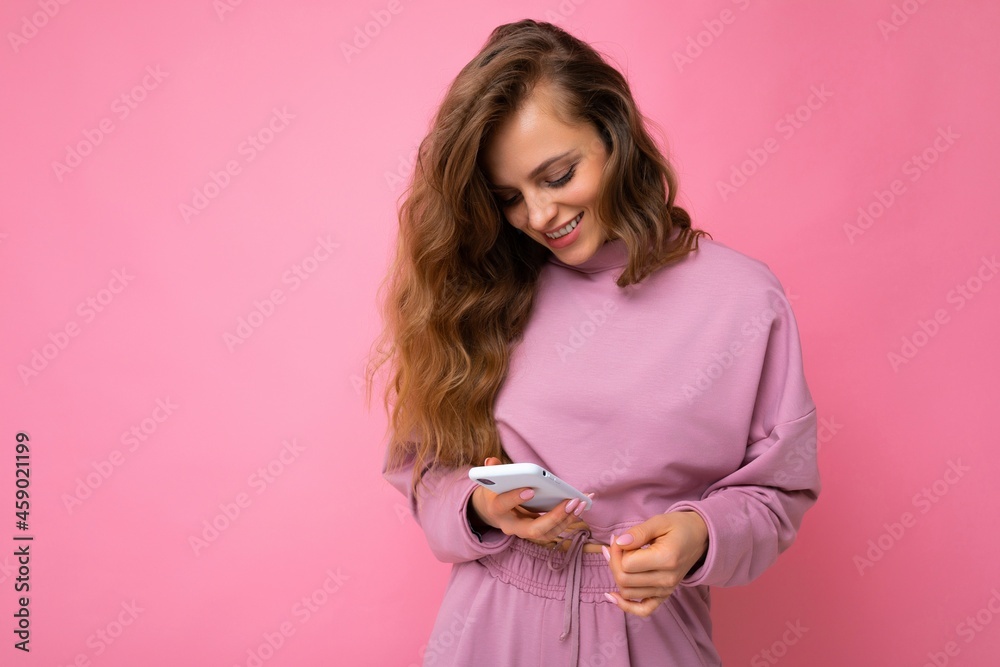 beautiful young blonde woman happy woman wearing casual clothes standing isolated over background surfing on the internet via phone looking at mobile screen beautiful young blonde woman happy woman wearing casual clothes standing isolated over background surfing on the internet via phone looking at mobile screen