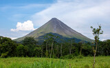 Volcano Arenal near tourist town of La Fortuna in Costa Rica. Cone-shaped volcano surrounded by jungle trees and cattle pasture.
