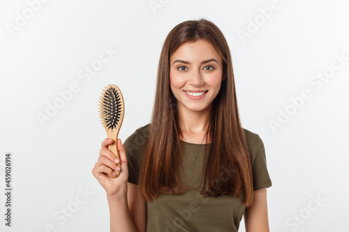 Happy young woman combing her long healthy hair on white background. photo