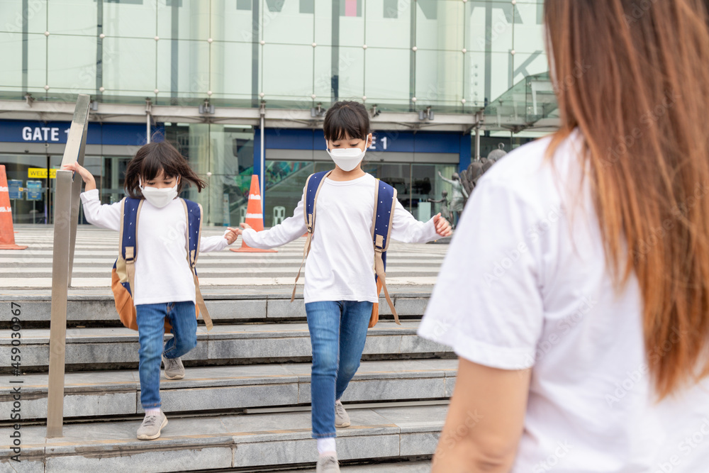 Portrait image of little cute Asian children siblings wearing a face mask and take a school bag. Back to school and kids. Childhood