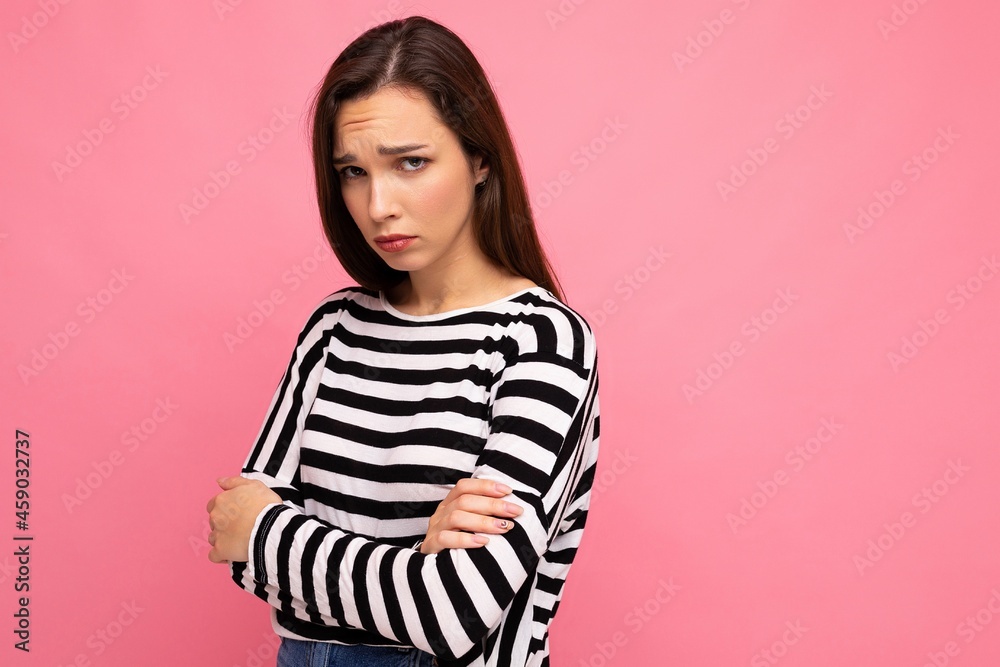 Portrait of cute attractive pretty young sad upset brunette woman wearing casual striped sweater isolated over colorful background with copy space Portrait of cute attractive pretty young sad upset brunette woman wearing casual striped sweater isolated over colorful background with copy space