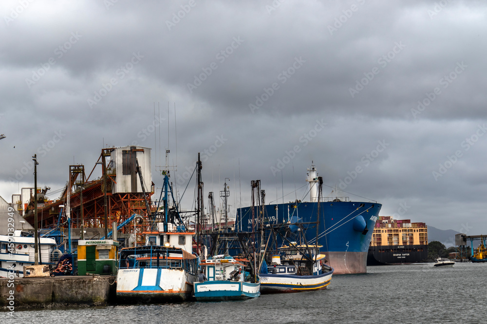 Fototapeta premium Santos, Sao Paulo, Brazil, September 17, 2021. Cargo ship from Hong Kong loaded with containers is towed through the channel of the Port of Santos, coast of Sao Paulo state, Brazil
