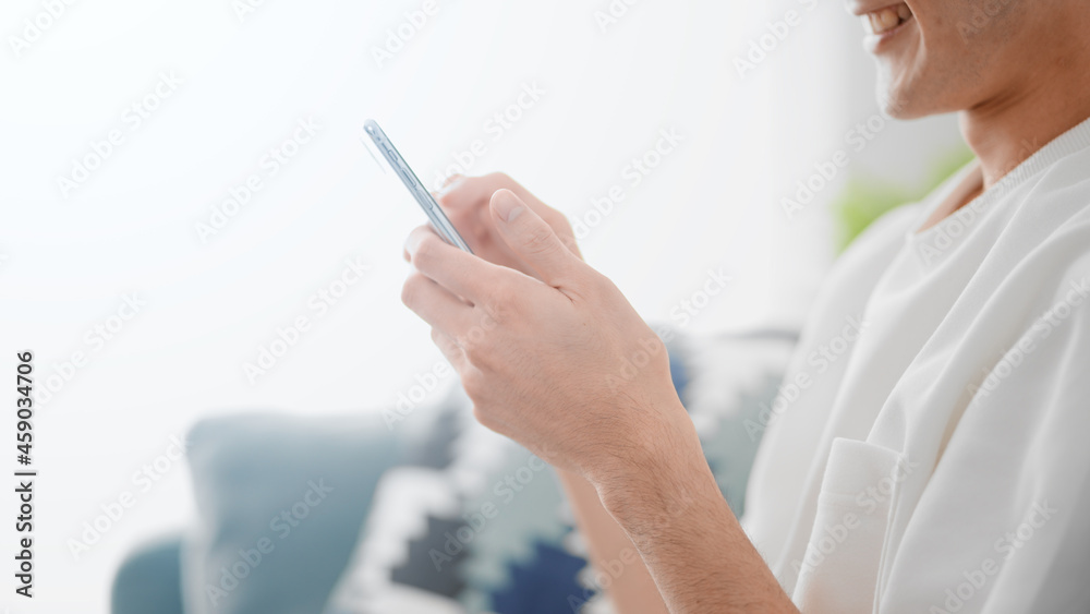 ソファーでスマートフォンを使う男性 ソファーでスマートフォンを使う男性