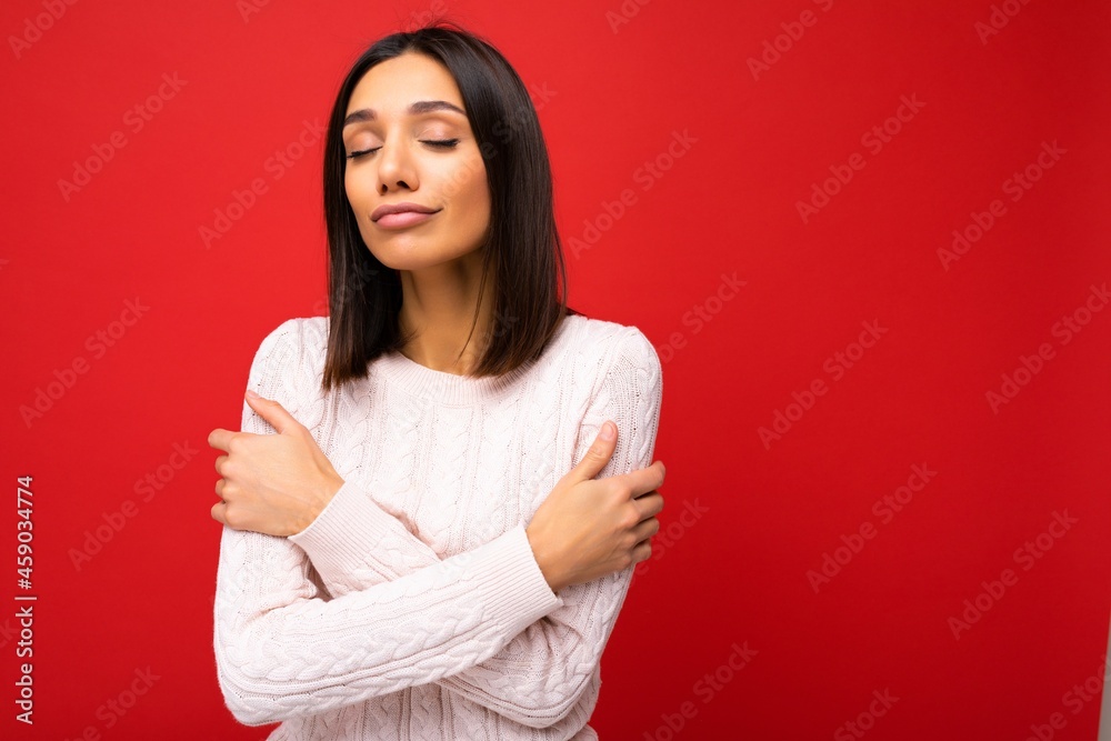 Beautiful cute nice adorable young brunet woman in stylish light knitted jersey isolated over red background wall with free space and enjoying Beautiful cute nice adorable young brunet woman in stylish light knitted jersey isolated over red background wall with free space and enjoying