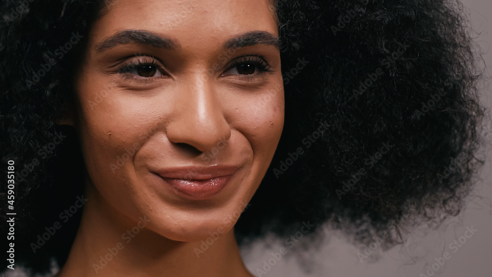close up of curly african american woman smiling isolated on grey close up of curly african american woman smiling isolated on grey