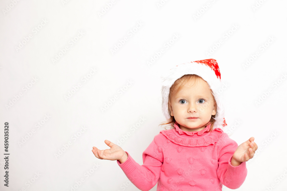 Portrait of a cute girl with blue eyes in a Christmas cap and a pink jumper. White background, space for text. New Year Portrait of a cute girl with blue eyes in a Christmas cap and a pink jumper. White background, space for text. New Year