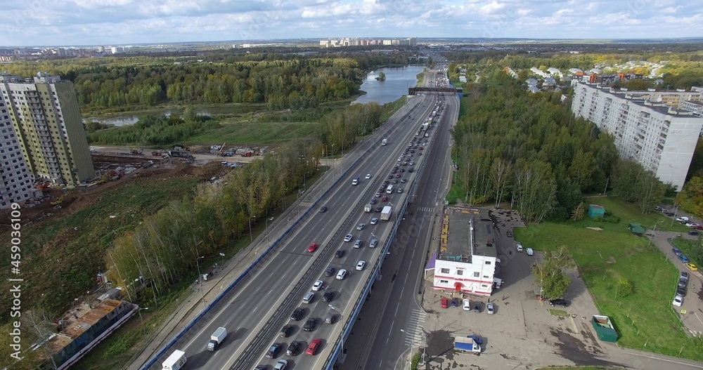 An aerial view of an endless highway with busy traffic in the middle of the green urban scenery